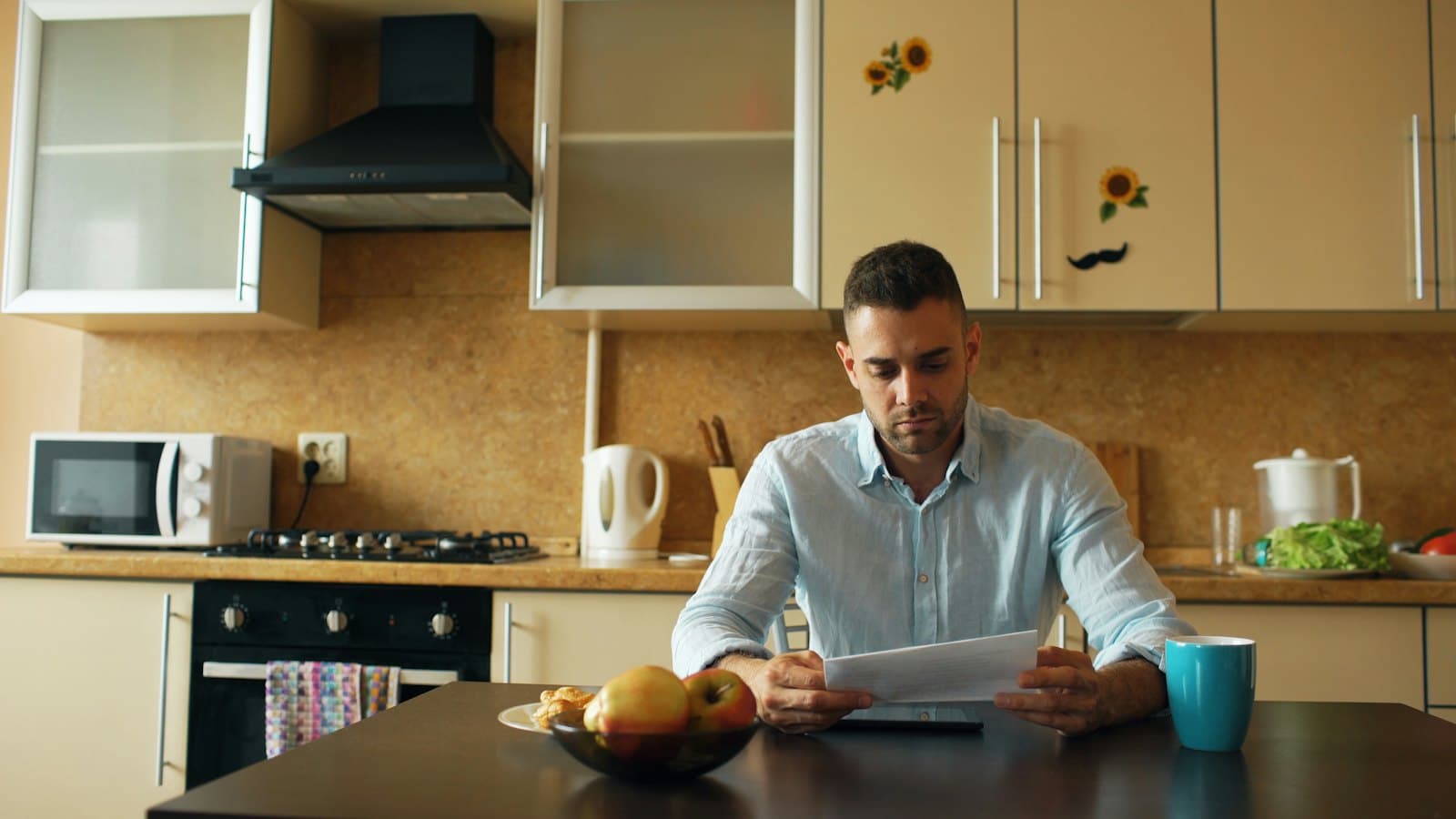 Man reading through a document at his kitchen table with a cup of coffee