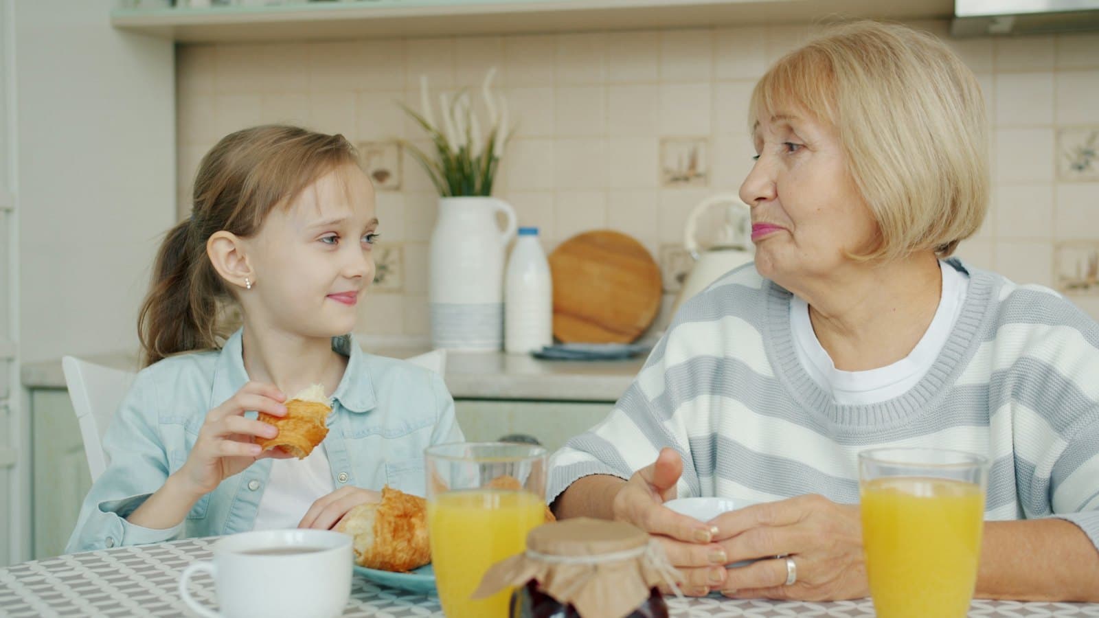 Grandmother and granddaughter sharing breakfast together at a home table