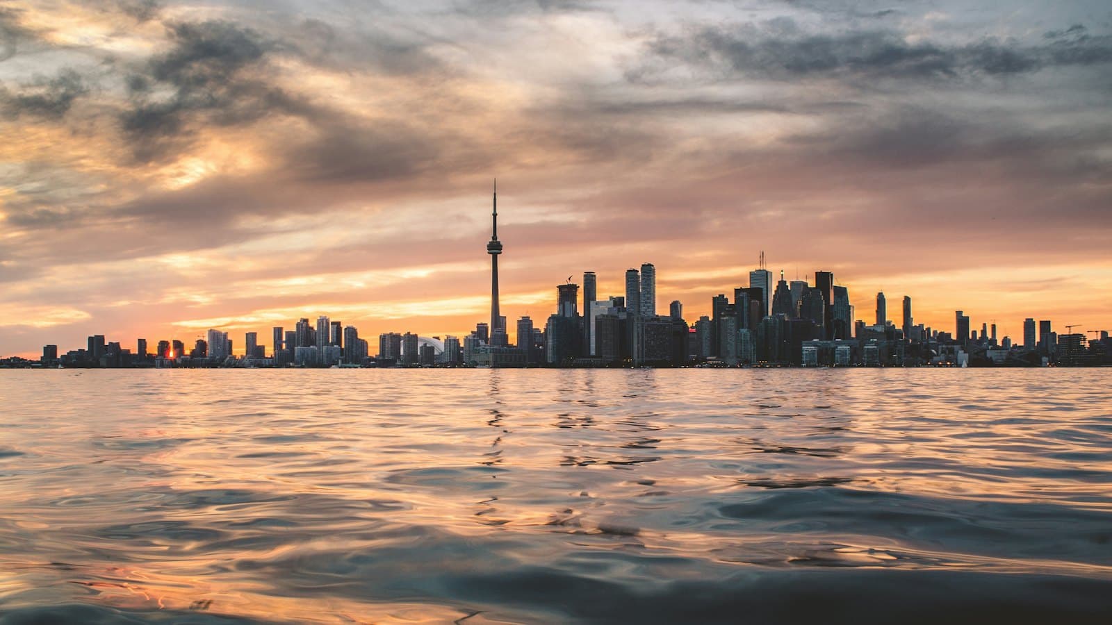 Toronto skyline and the CN Tower seen across Lake Ontario at sunset