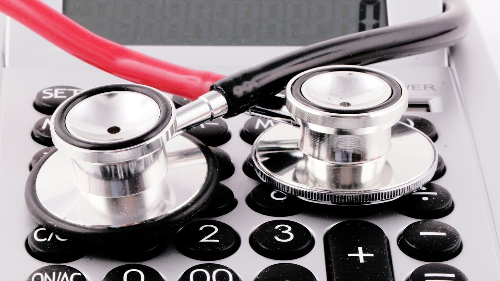 Stethoscope resting on top of a calculator on a desk
