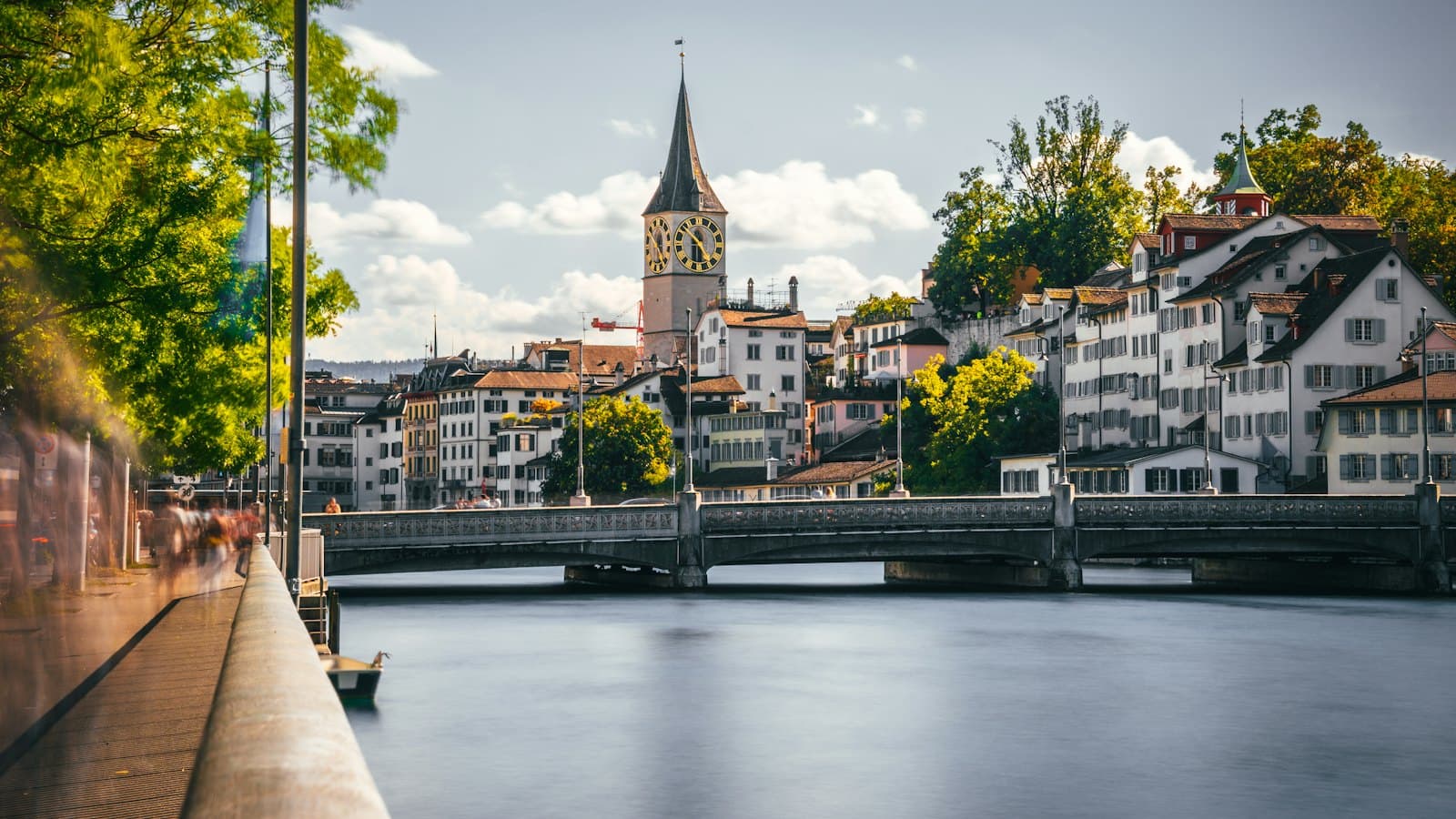 Zurich old town with a church clock tower and stone bridge over the Limmat river
