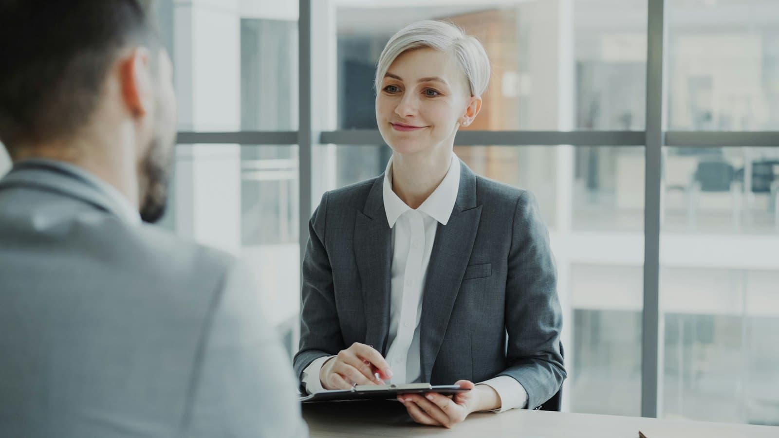 A woman in a suit interviewing a man across a table