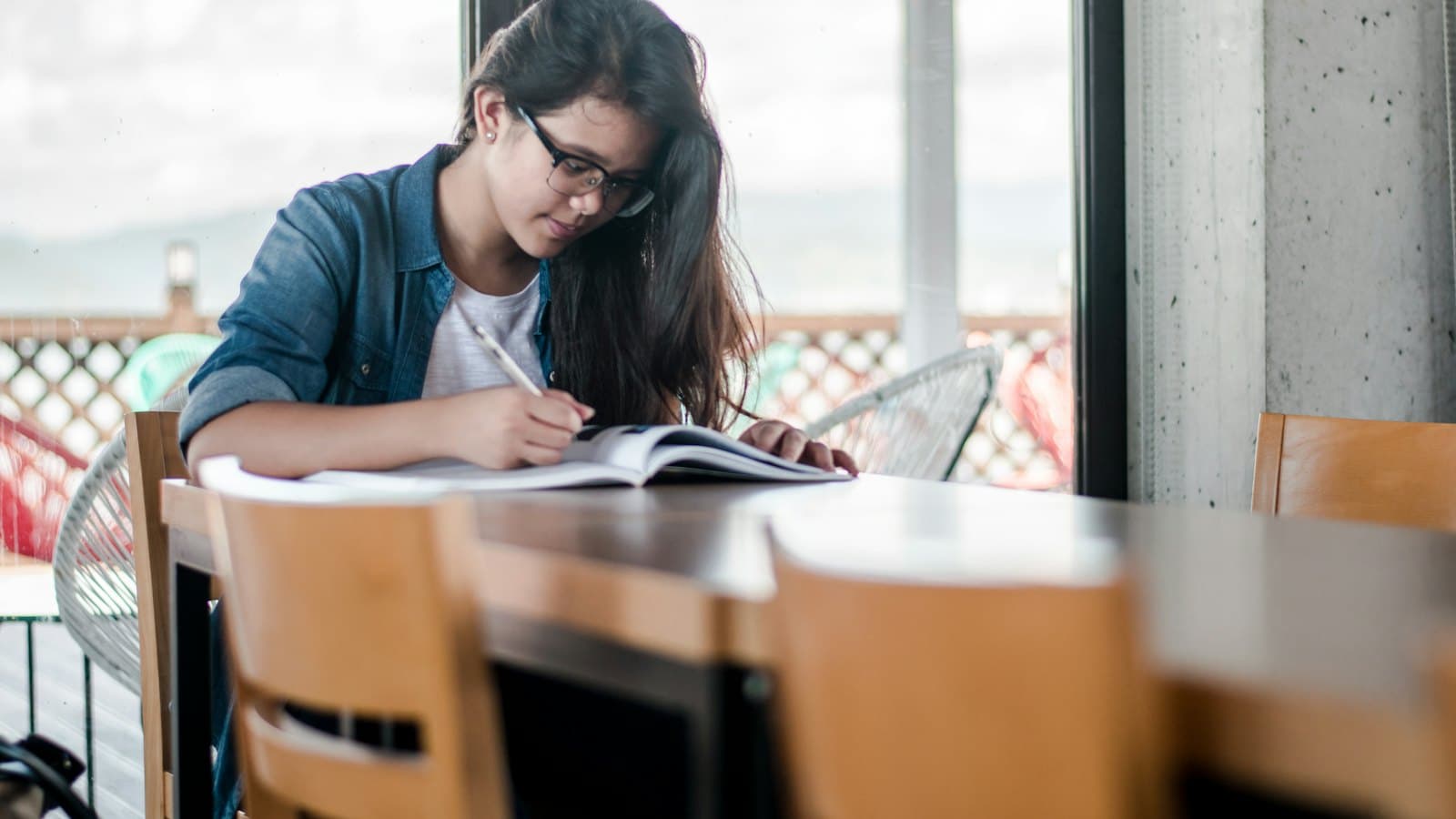 A woman writing notes in a book while studying at a desk