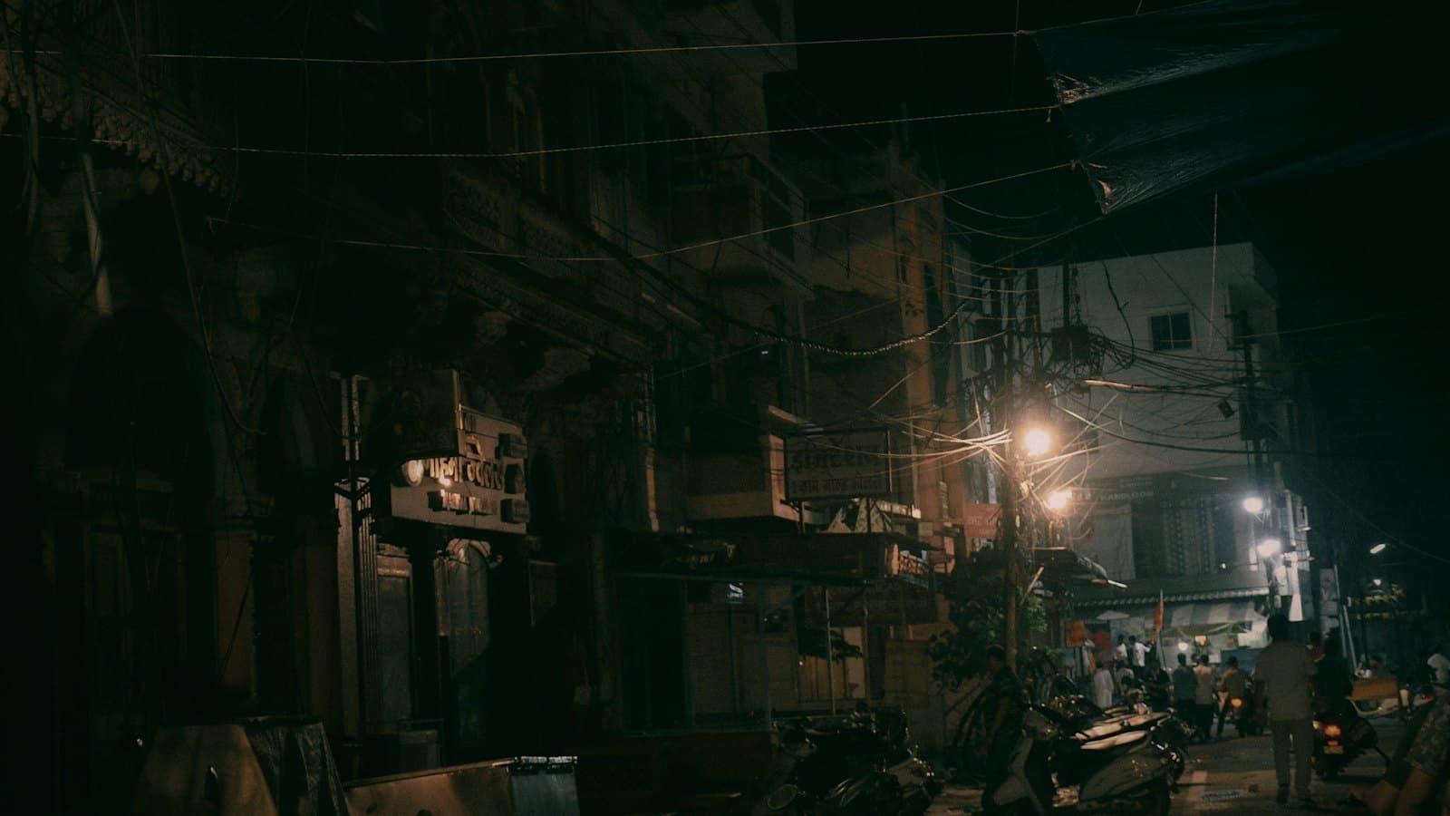 Dark narrow street at night with tangled overhead power wires