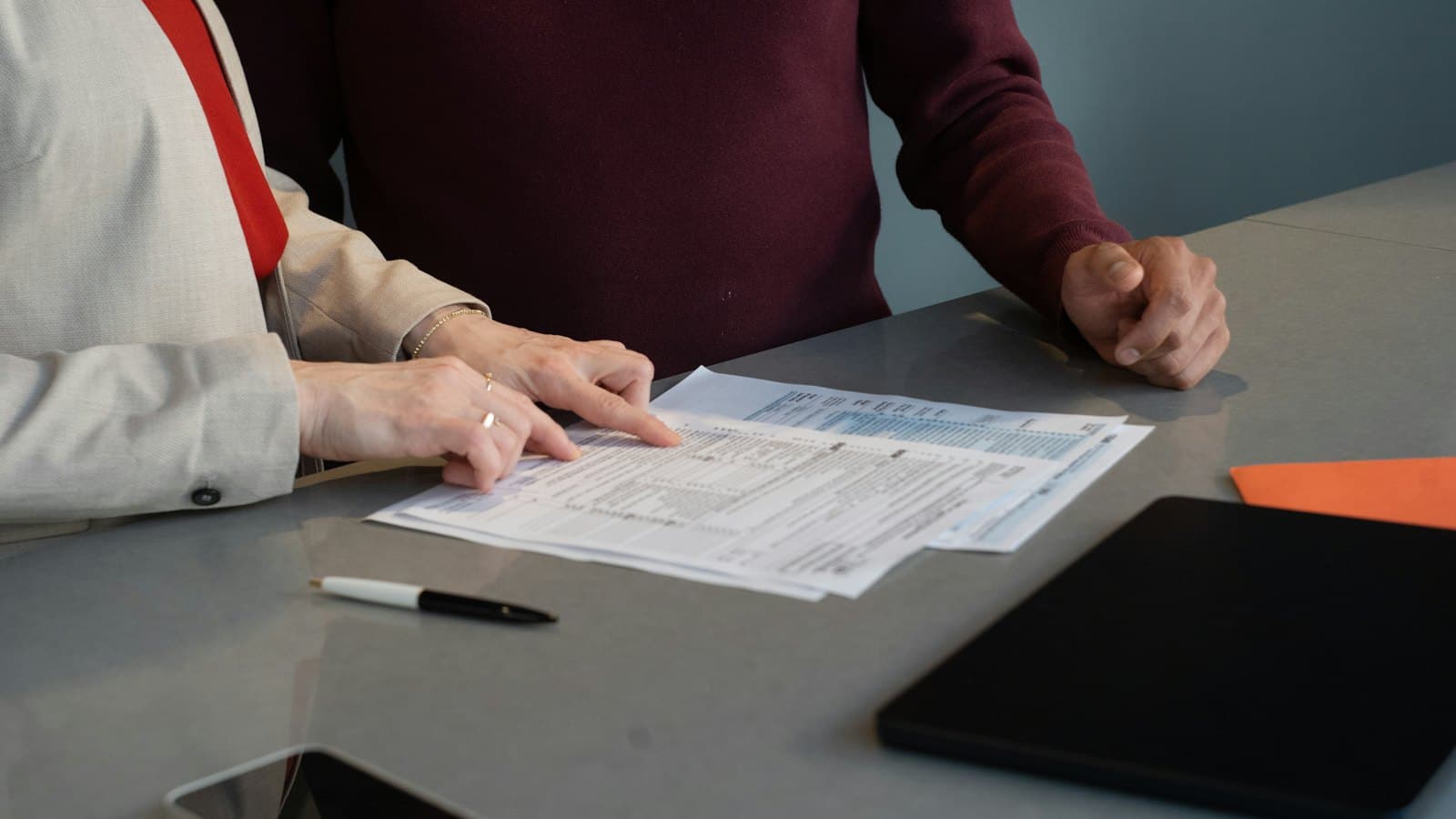 Two people reviewing printed documents together at a table