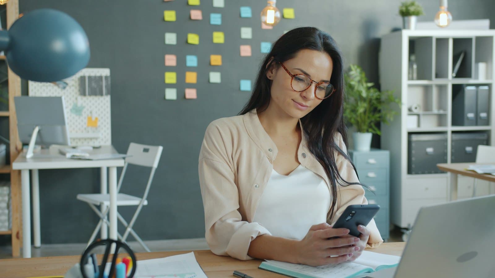 A woman checking her phone while sitting in a bright office