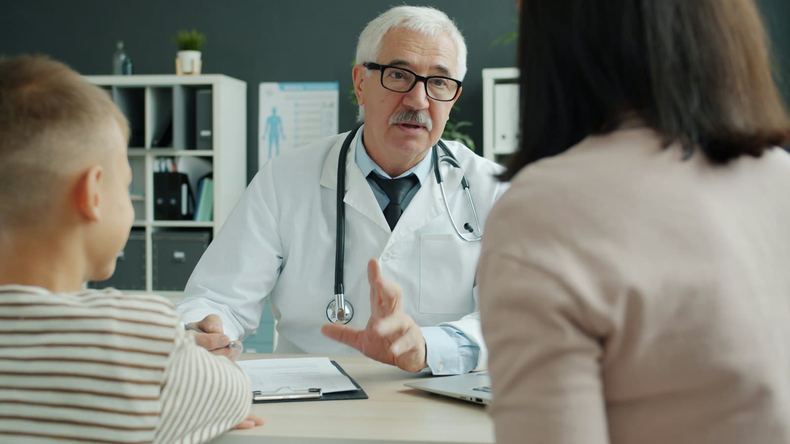 Doctor speaking with a mother and her young child in a clinic office