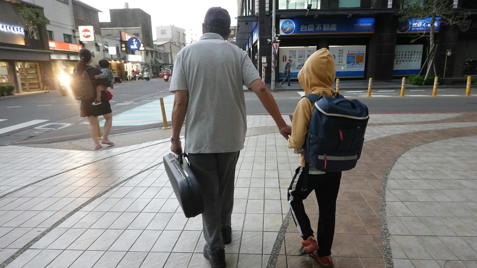 Adult walking hand in hand with a child carrying a school backpack