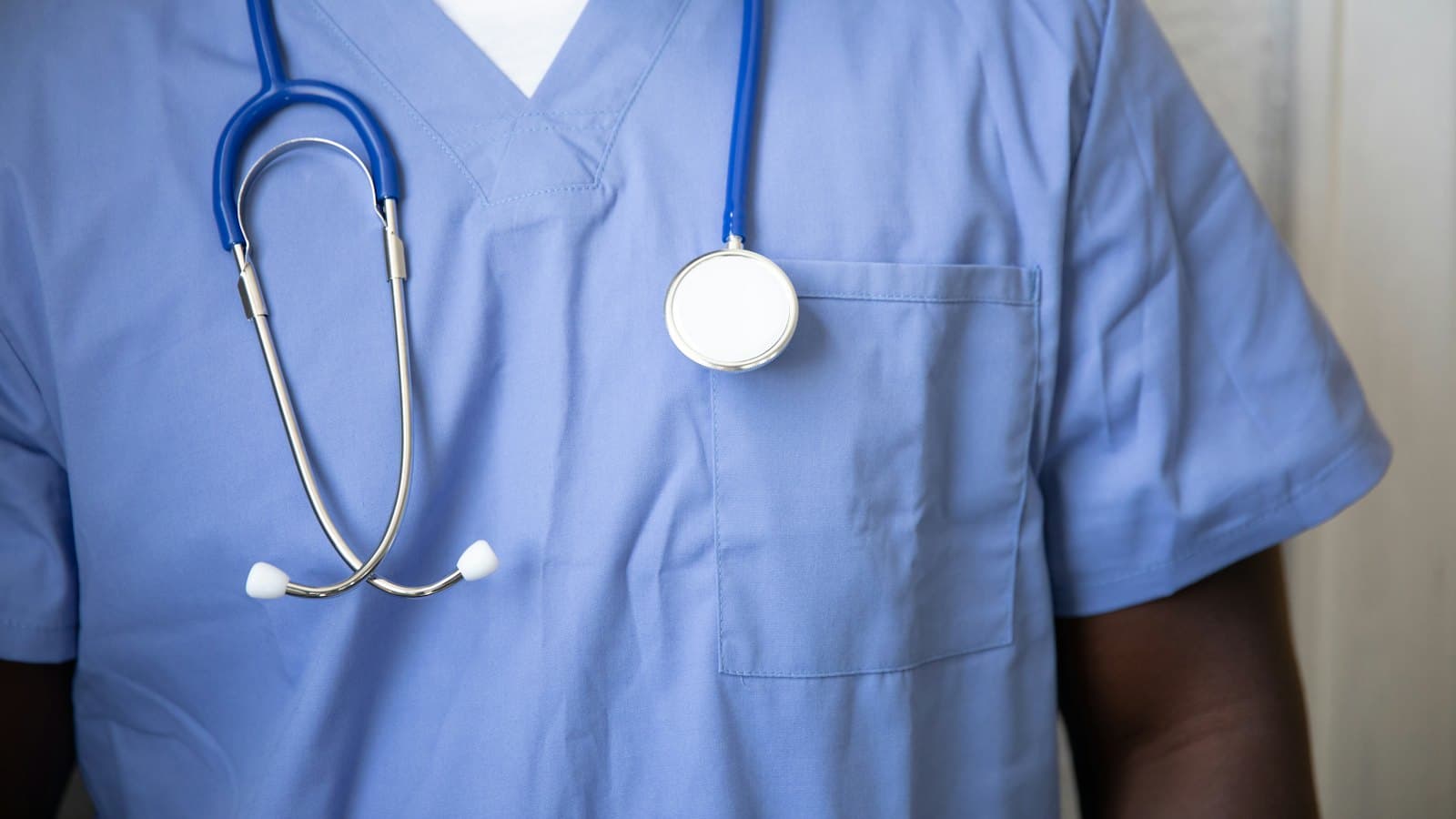 Close-up of a nurse in blue scrubs with a stethoscope draped around the neck