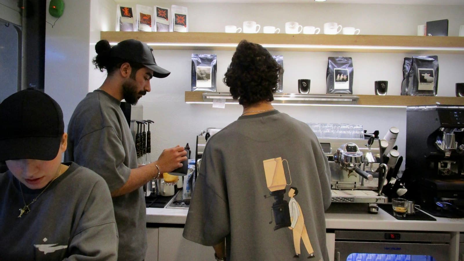 Young baristas making coffee behind a busy cafe counter
