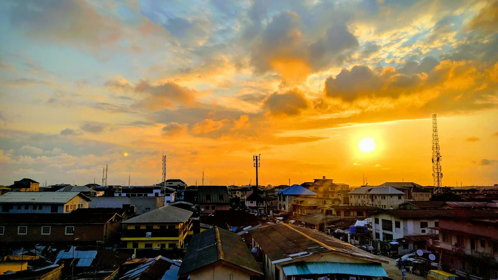 Sunset over the rooftops and phone masts of a busy West African city