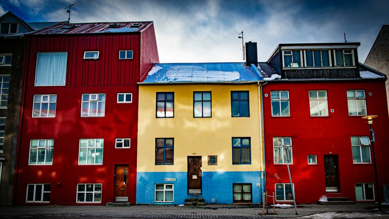 Red and yellow painted houses with snow on the roofs along a quiet city street