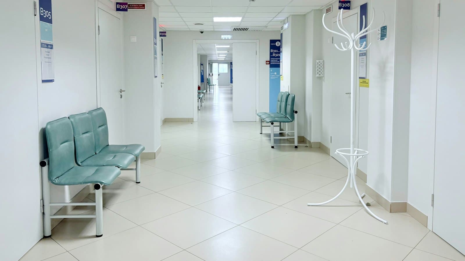 Quiet hospital corridor with benches along the wall and closed doors