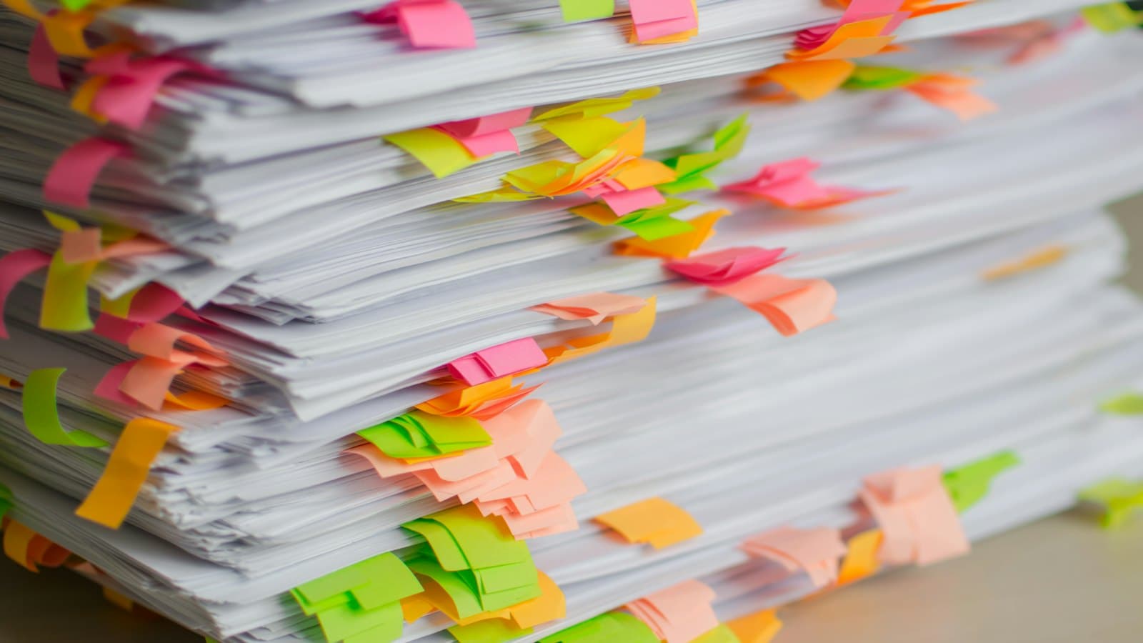 A thick stack of paperwork marked with colourful sticky tabs