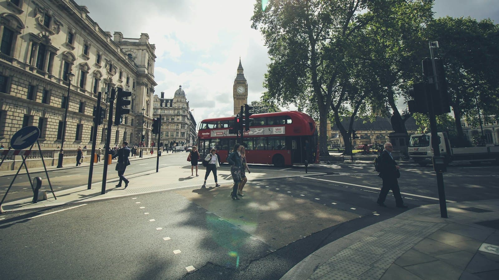 People crossing Whitehall in London with Big Ben and a red bus behind