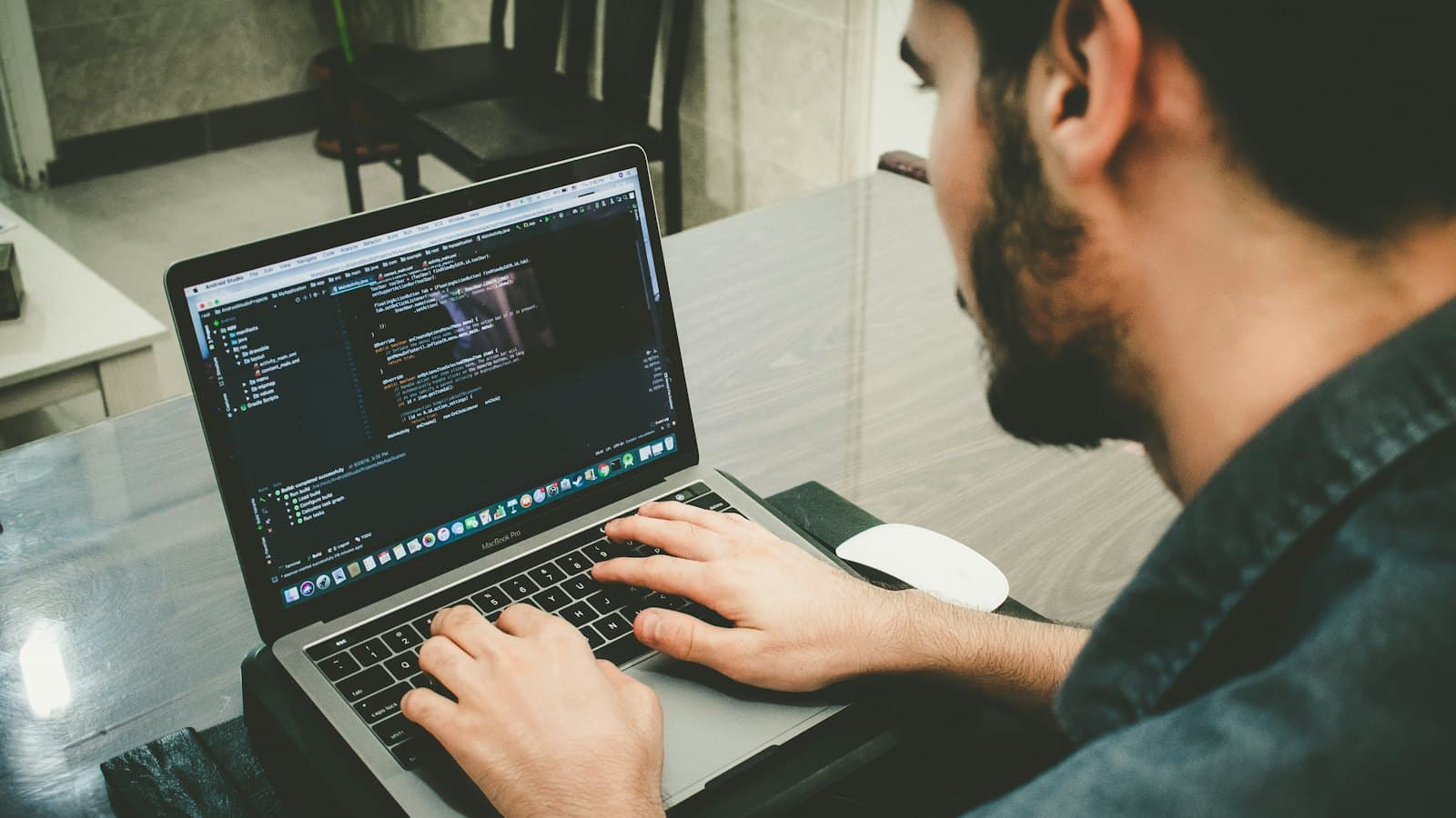 A software developer writing code on a laptop at his desk