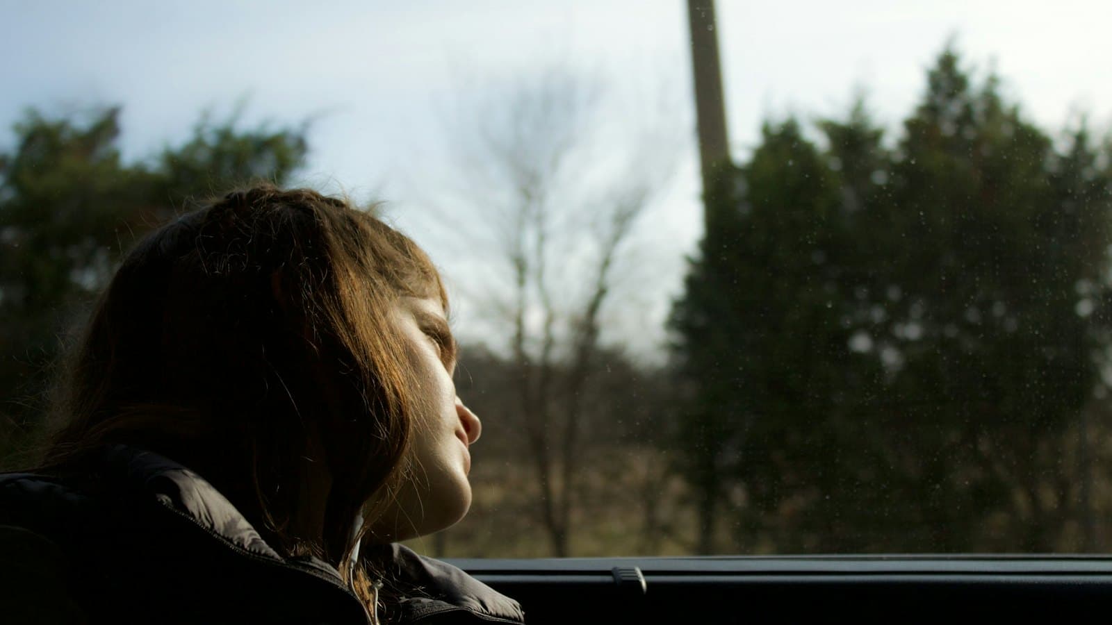 Young girl in the back seat of a car gazing out the window