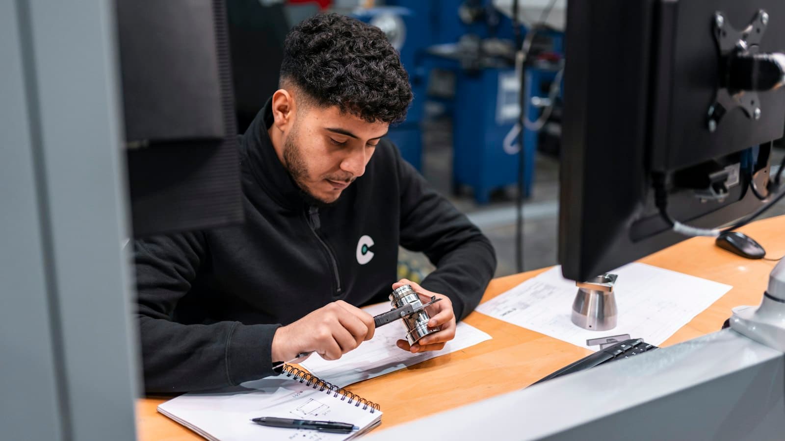 An engineer carefully measuring a machined metal component in a workshop