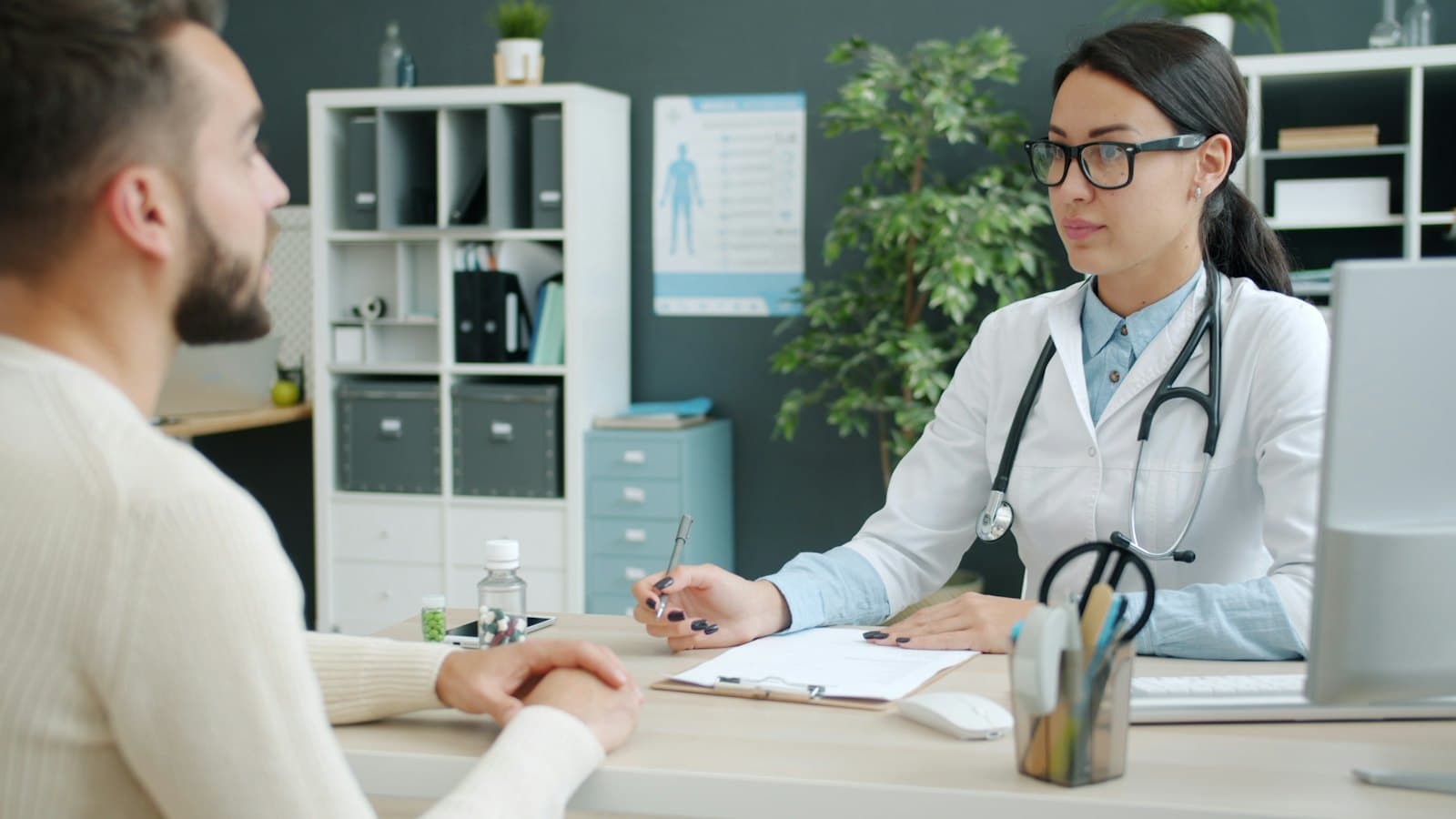 A doctor consulting with a patient across a desk in a clinic office