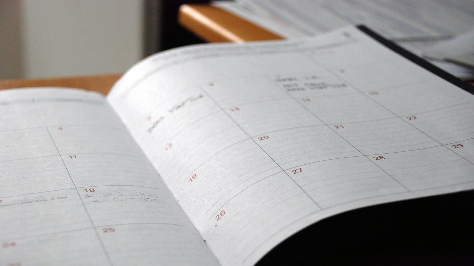 An open monthly planner on a wooden desk for tracking appointment dates