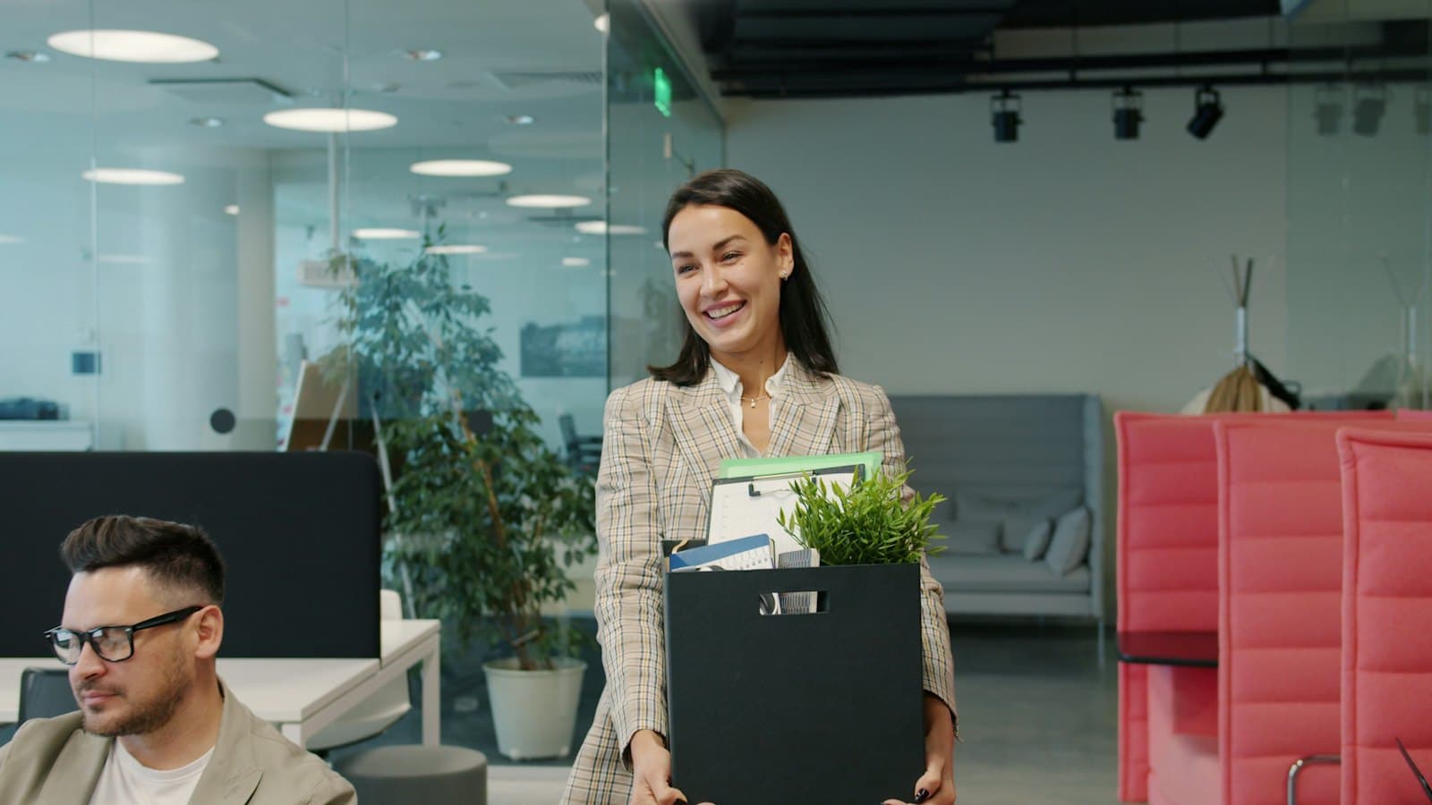 A woman carrying a box of her belongings as she leaves the office
