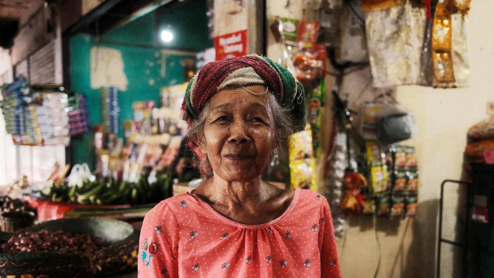 An elderly woman standing behind the counter of her small shop