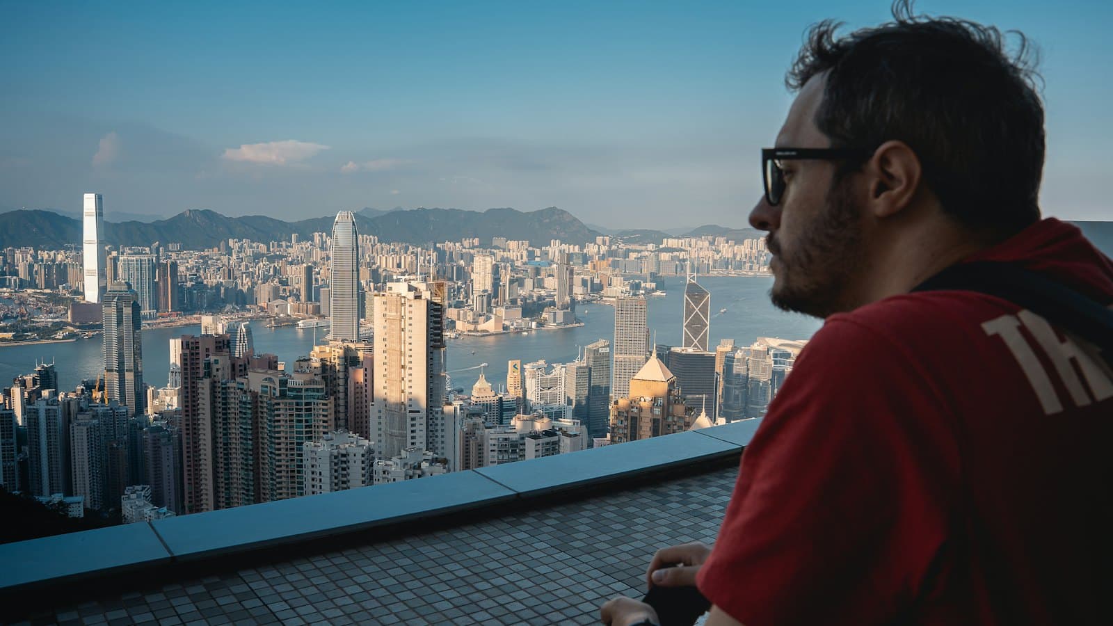A man looking out over the Hong Kong skyline and harbour from a viewpoint