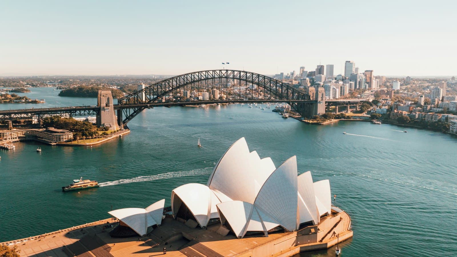 Sydney Opera House beside the harbour on a clear sunny day