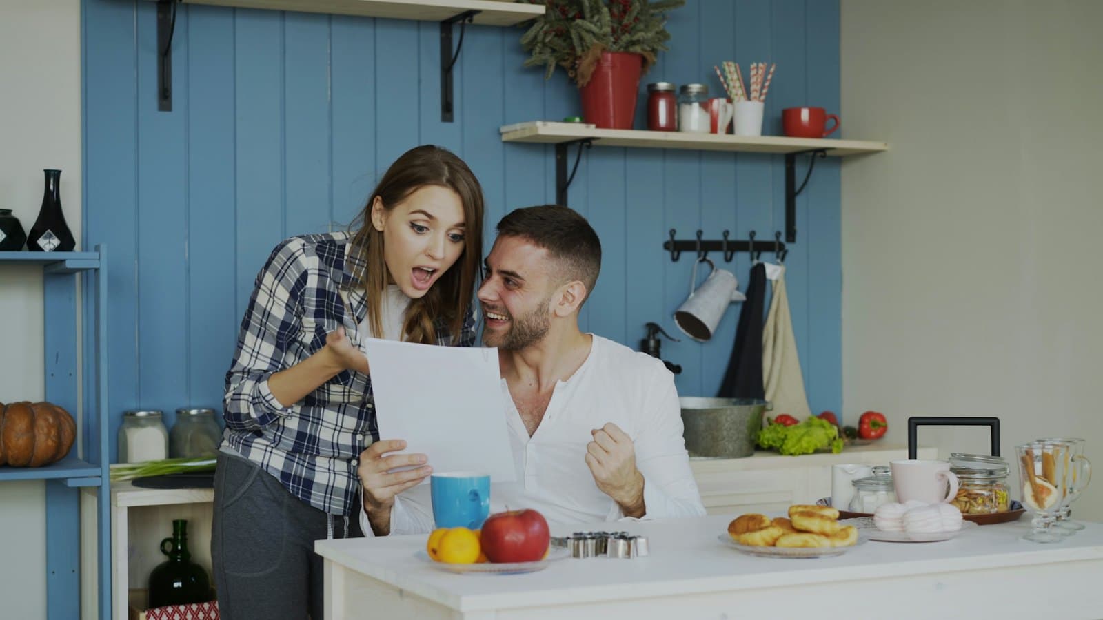 A couple sitting together at home, smiling as they read a document
