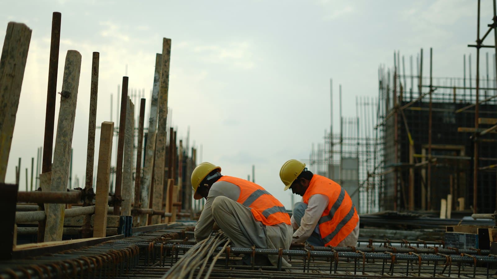 Construction workers in hard hats and safety vests working on a building site