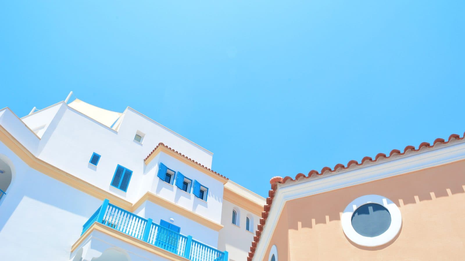 White and peach apartment buildings with blue shutters and balconies against a clear sky in Limassol, Cyprus