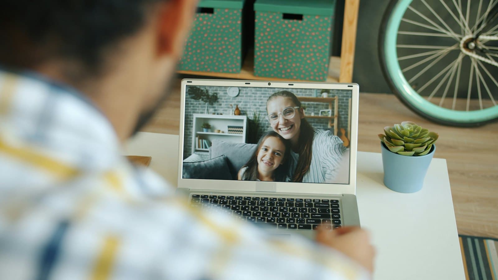 A man on a video call with a woman and young child on his laptop