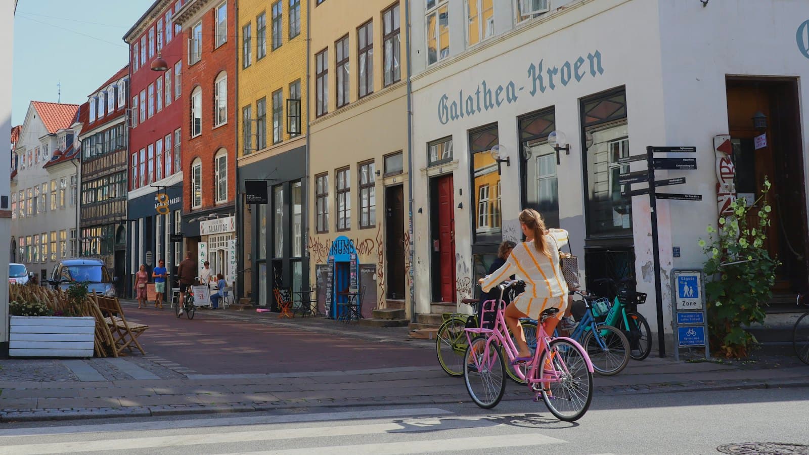 A woman cycling down a Copenhagen street lined with tall buildings