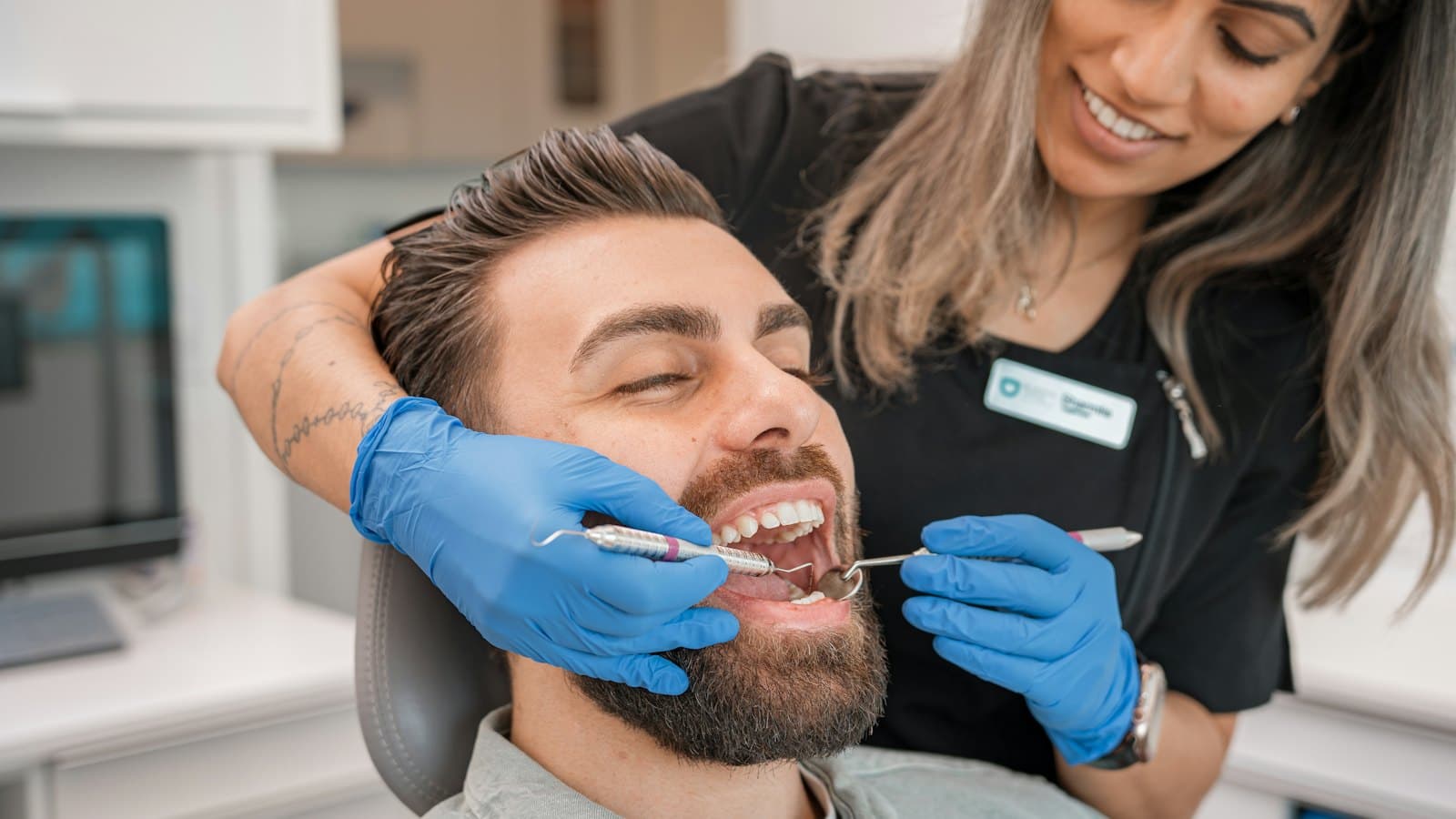 Dentist in blue gloves examining a patient's teeth in a dental office