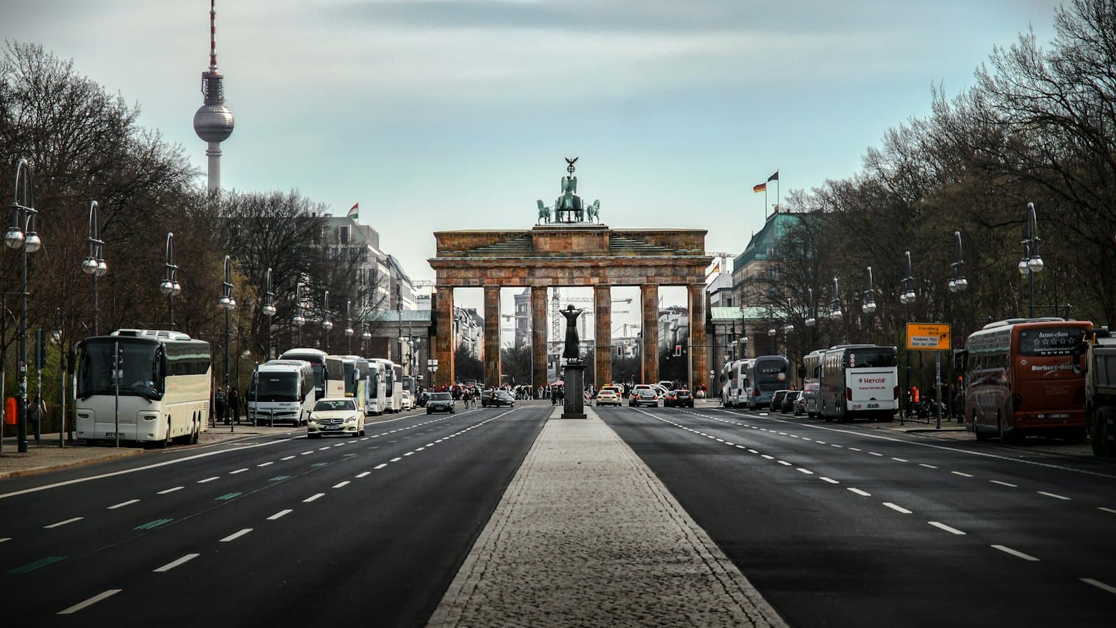 The Brandenburg Gate and Berlin TV Tower under a cloudy sky
