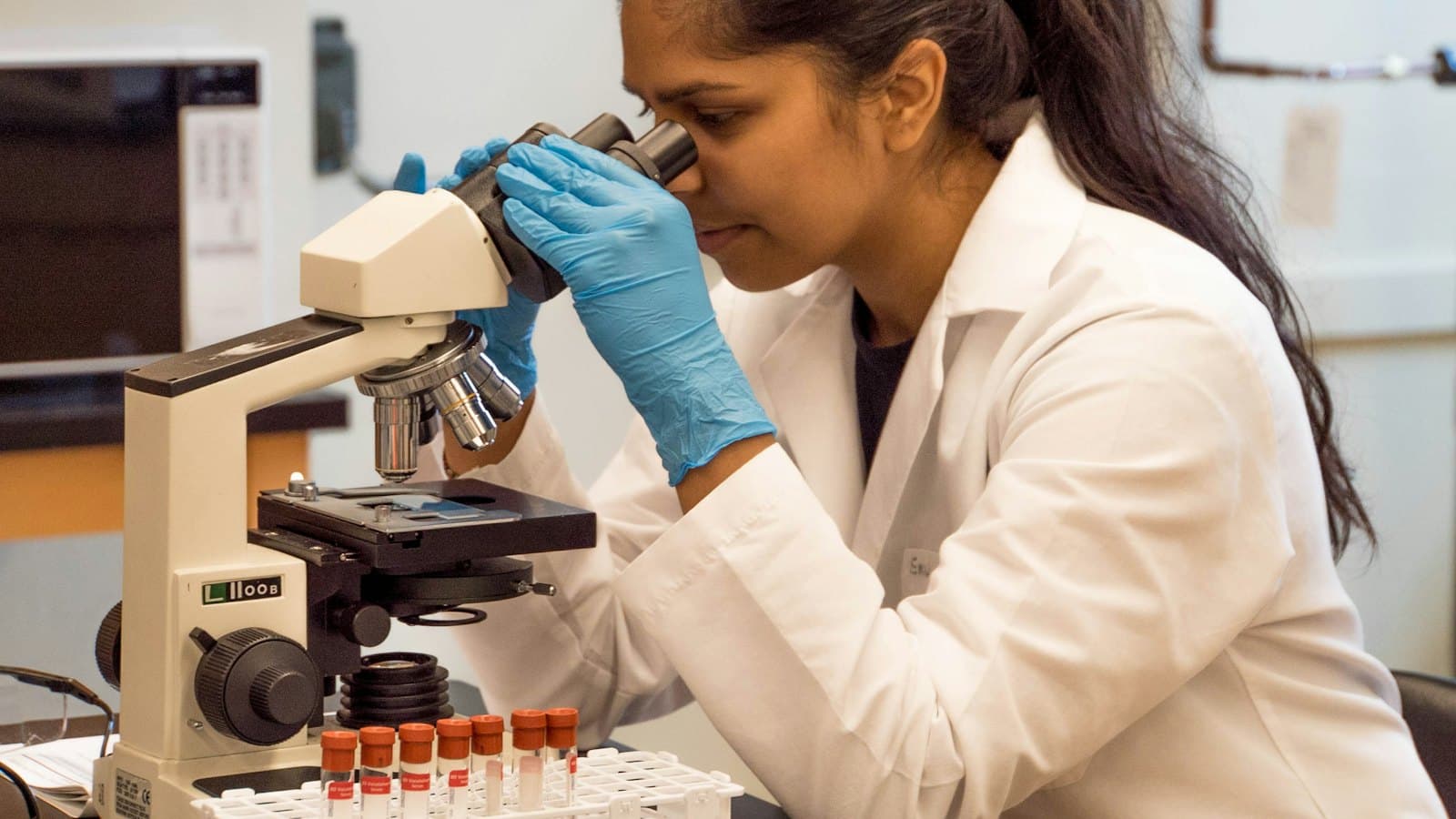 Woman in a laboratory looking through a microscope