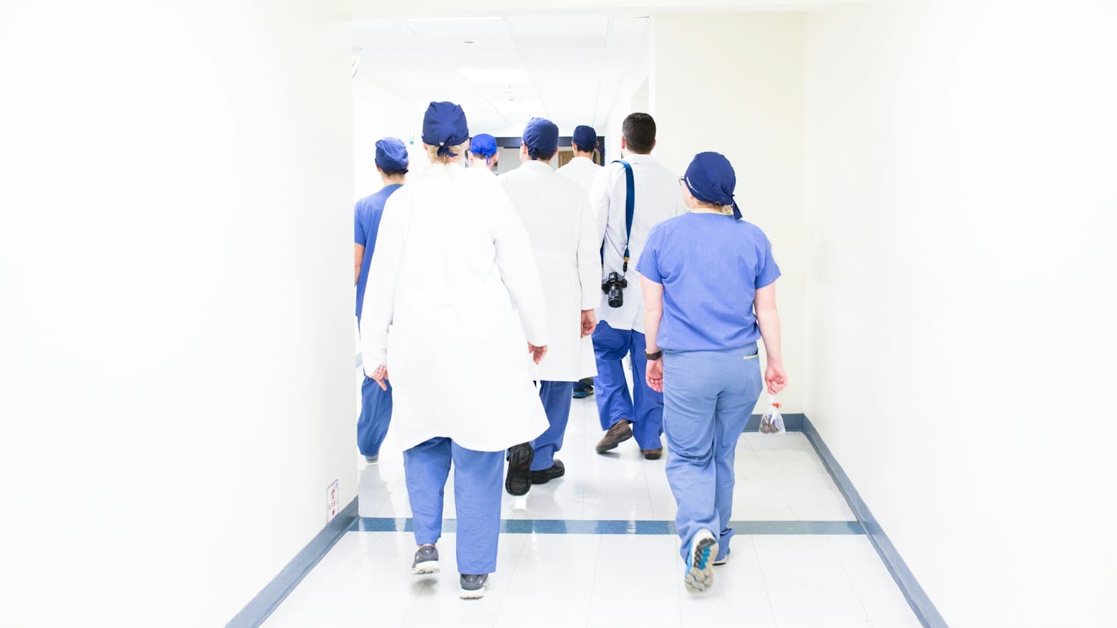 Doctors and surgeons in scrubs and white coats walking down a hospital corridor