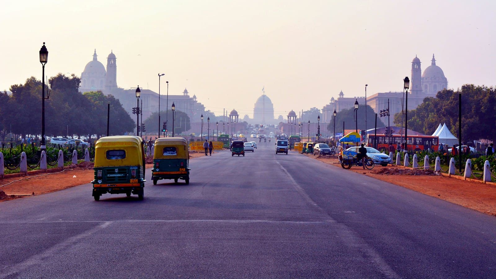 Auto rickshaws driving along a wide avenue toward Rashtrapati Bhavan in New Delhi