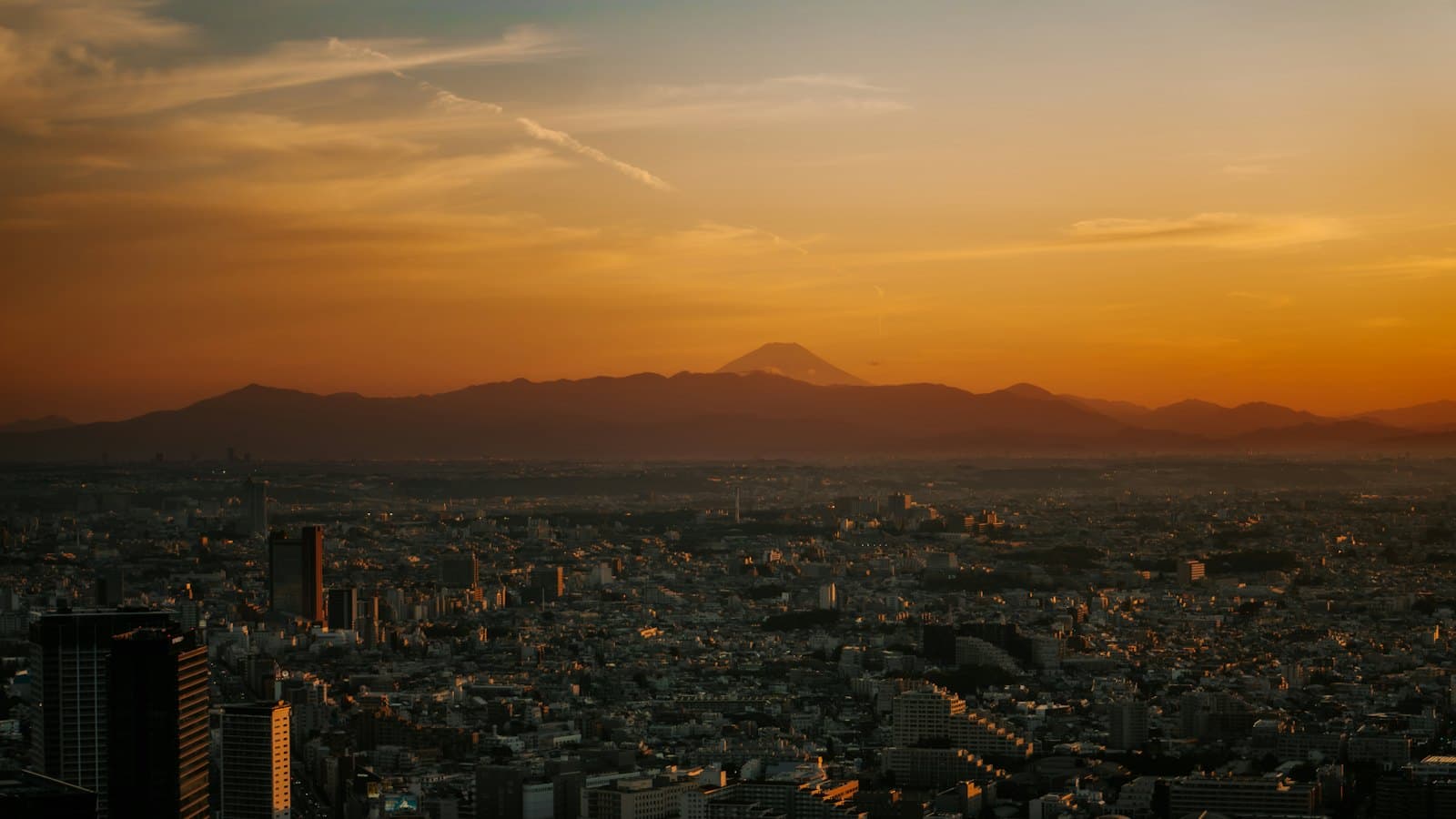 Orange sunset over the vast Tokyo cityscape with Mount Fuji in the distance