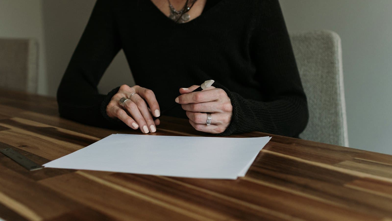 Woman seated at a wooden table with a sheet of paper in front of her