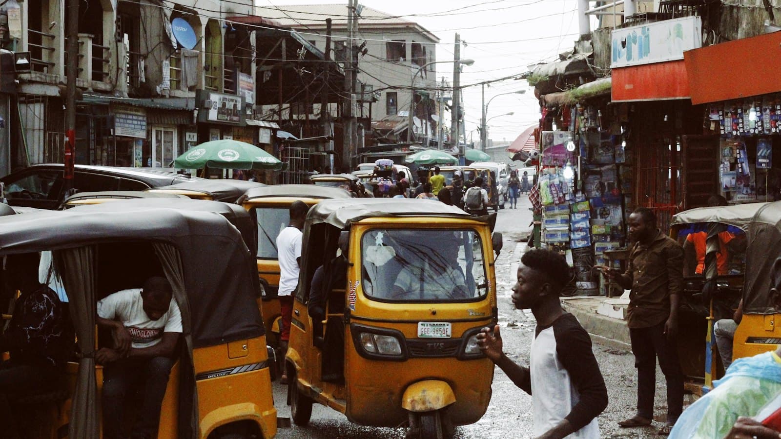 Yellow keke tricycles and pedestrians on a busy Lagos market street