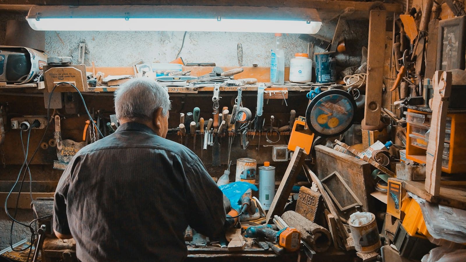 A man concentrating on a task at a workbench in his workshop