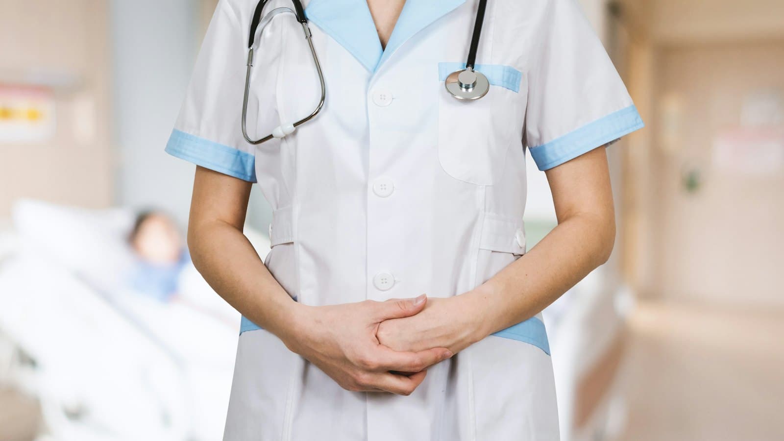 A nurse in a white uniform with a stethoscope standing in a hospital ward