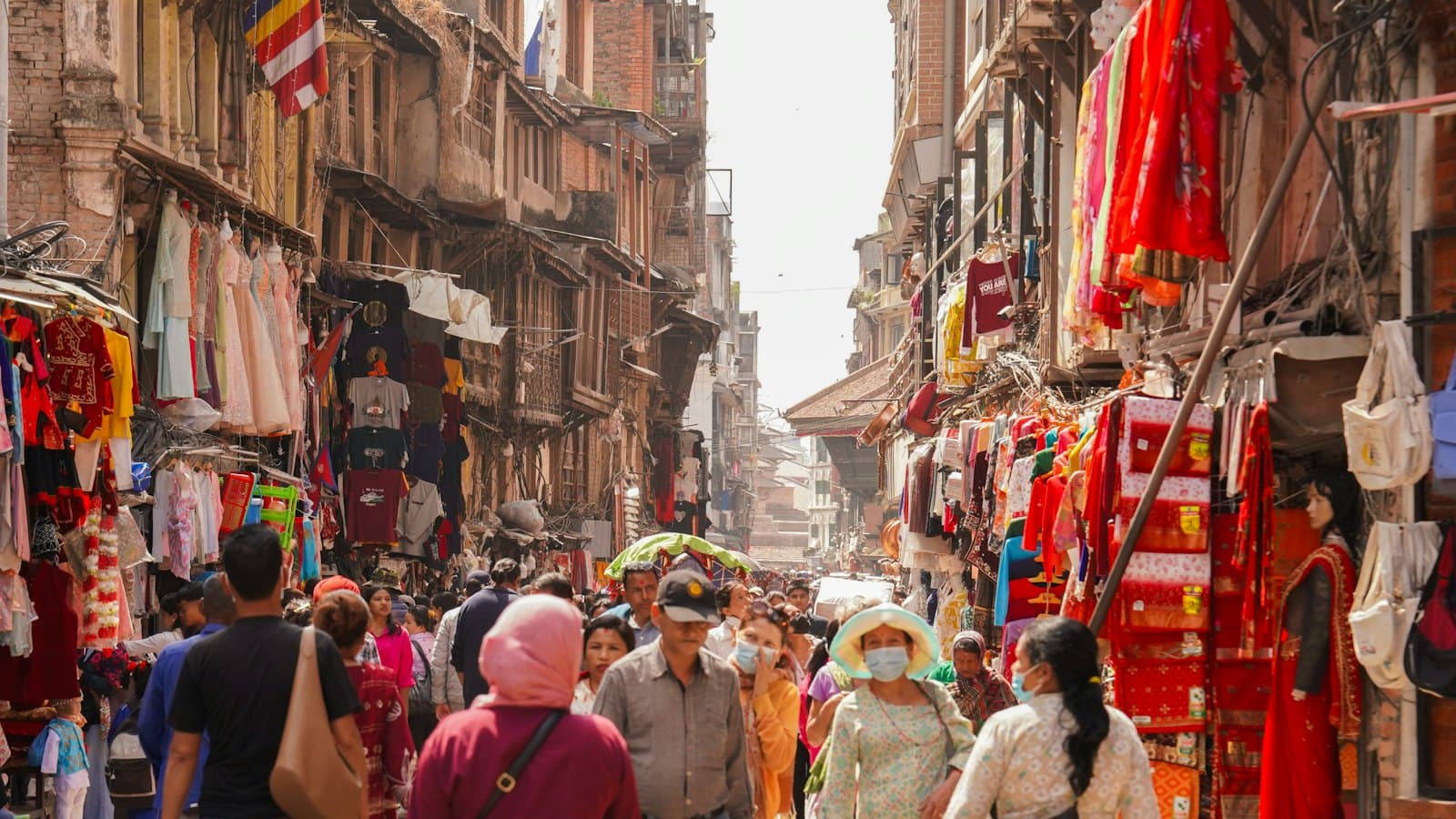 A crowded street market lined with colourful textiles and goods