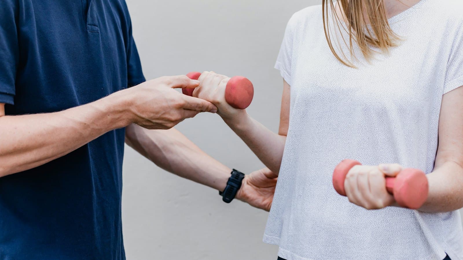 Physiotherapist guiding a patient through a dumbbell exercise in a clinic