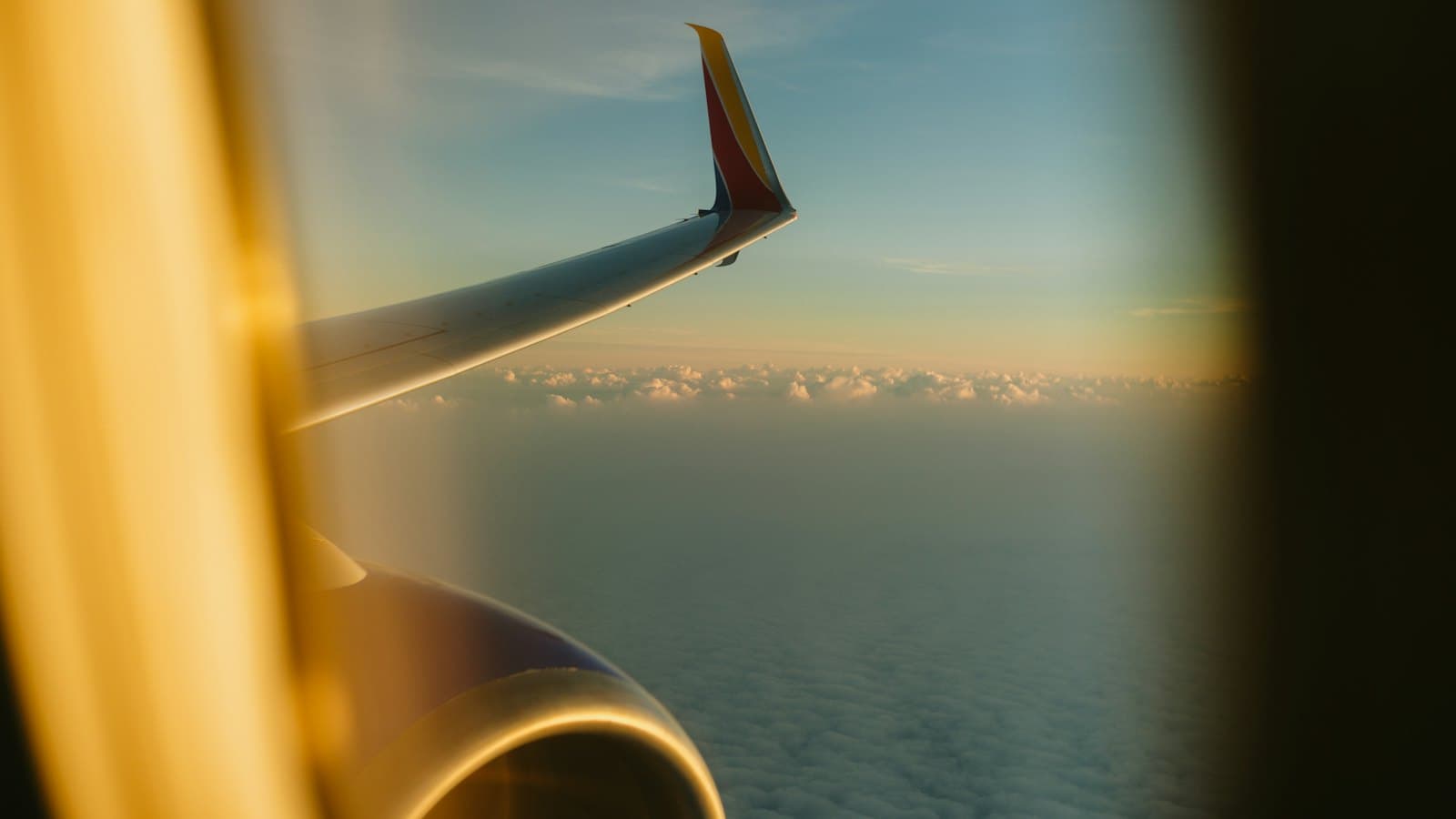 View of an airplane wing above the clouds at sunset