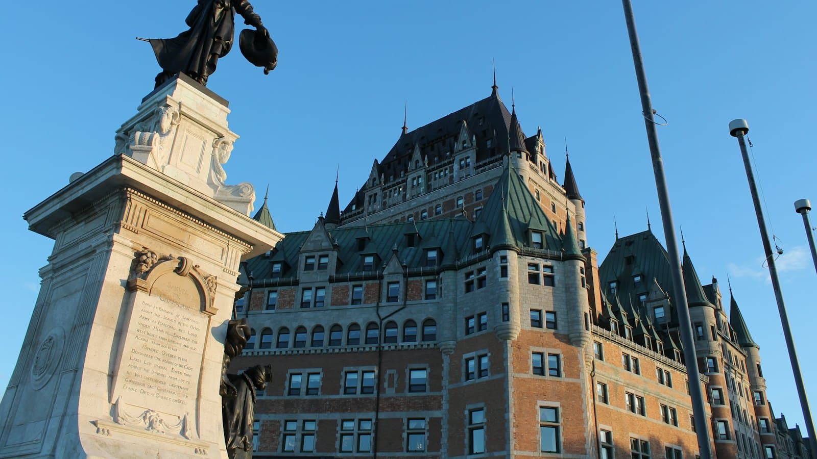 Chateau Frontenac hotel and a monument in Quebec City under a clear blue sky