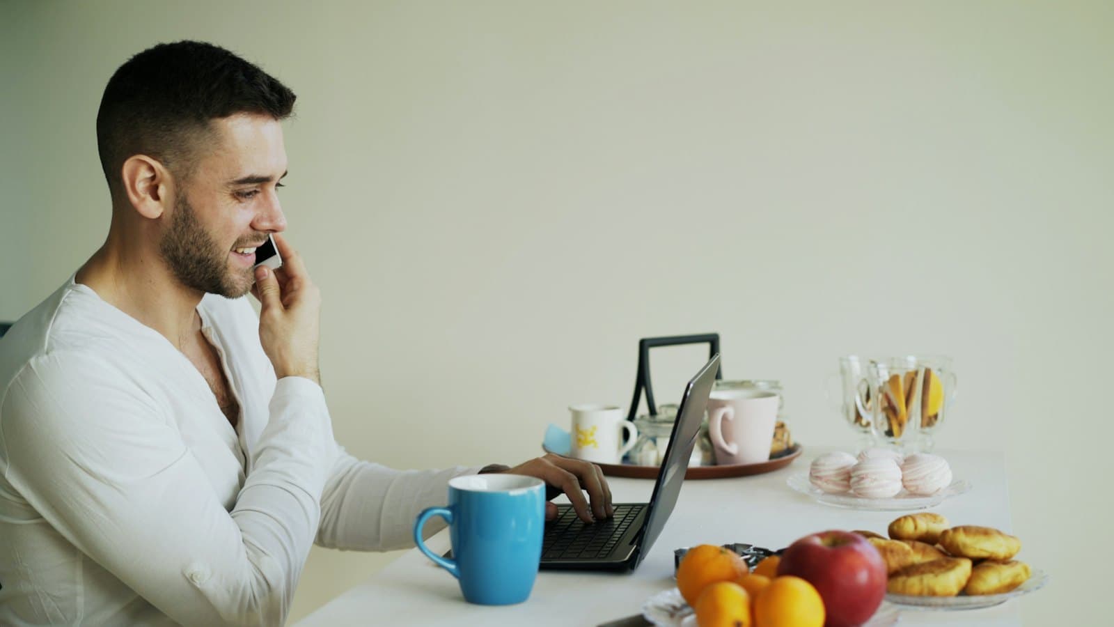 Man talking on the phone while working on a laptop at a table