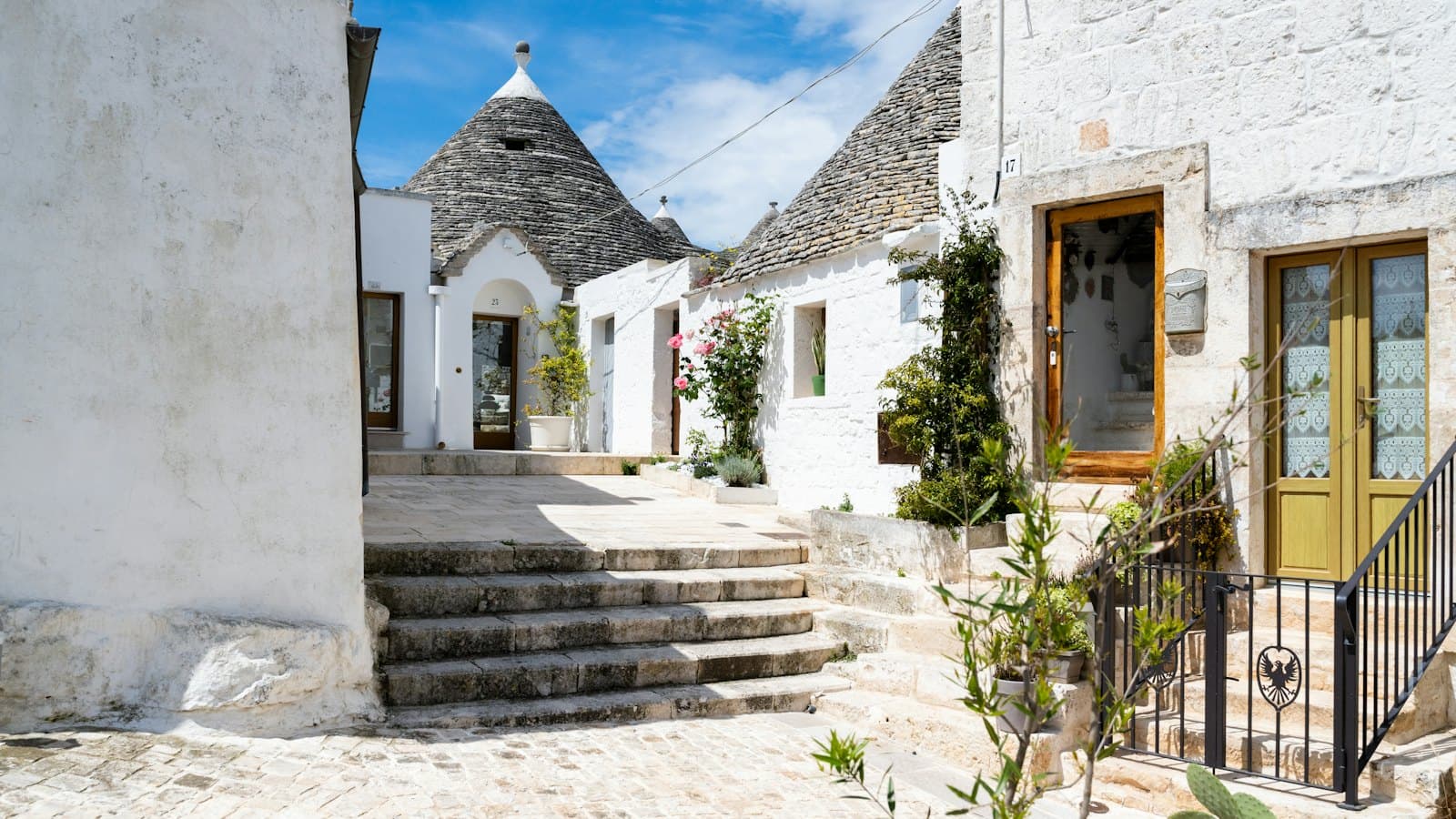 White trulli houses with conical stone roofs along a quiet village street in Puglia
