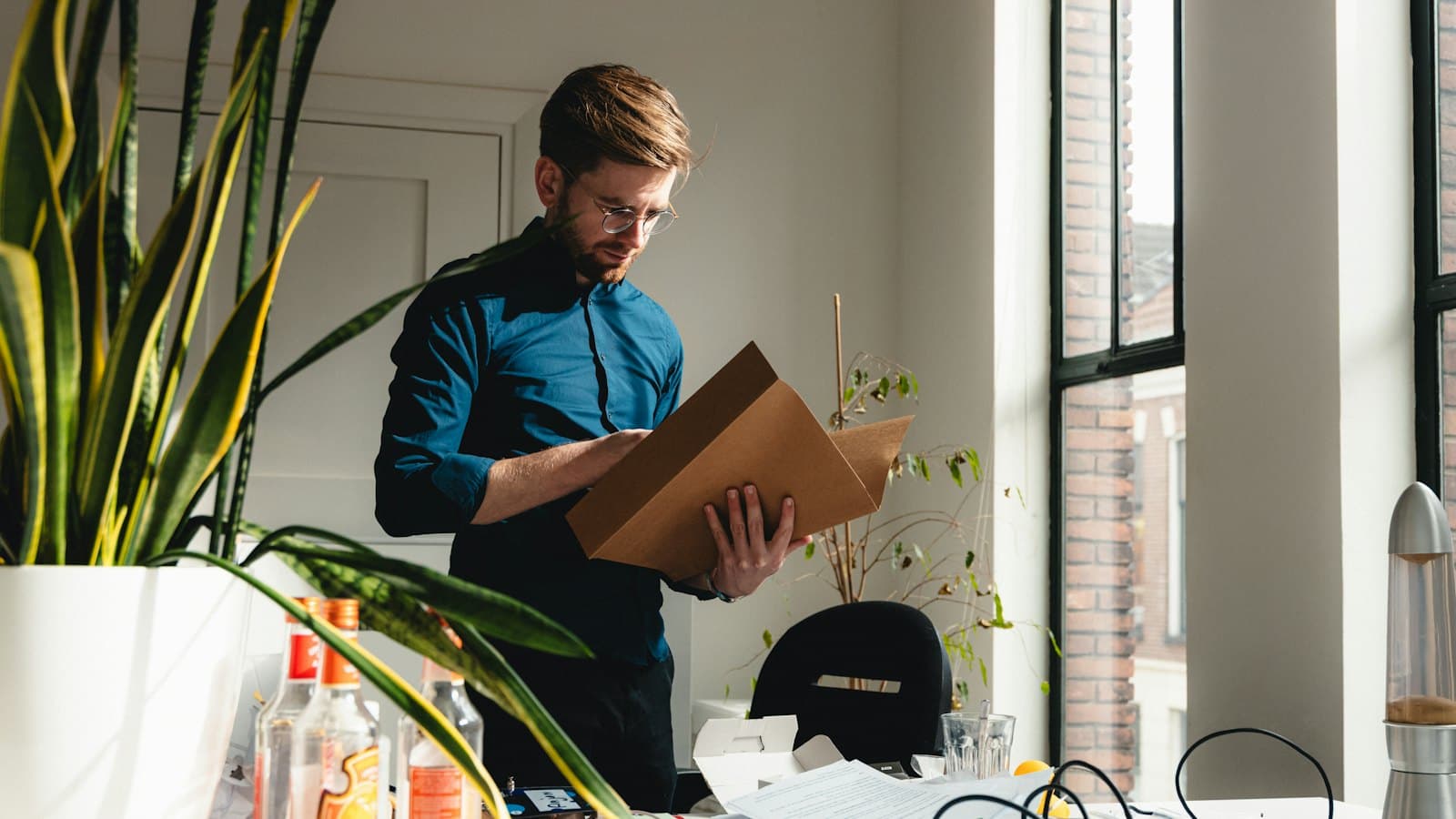 Man in an office reading through papers in a brown folder